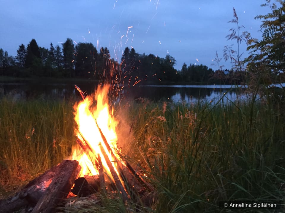 Midsummer bonfire to drive away evil spirits at river Kymi in white summer night