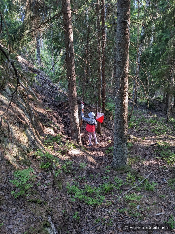 A child learning orienteering skills has just found a colourful check point to stamp.