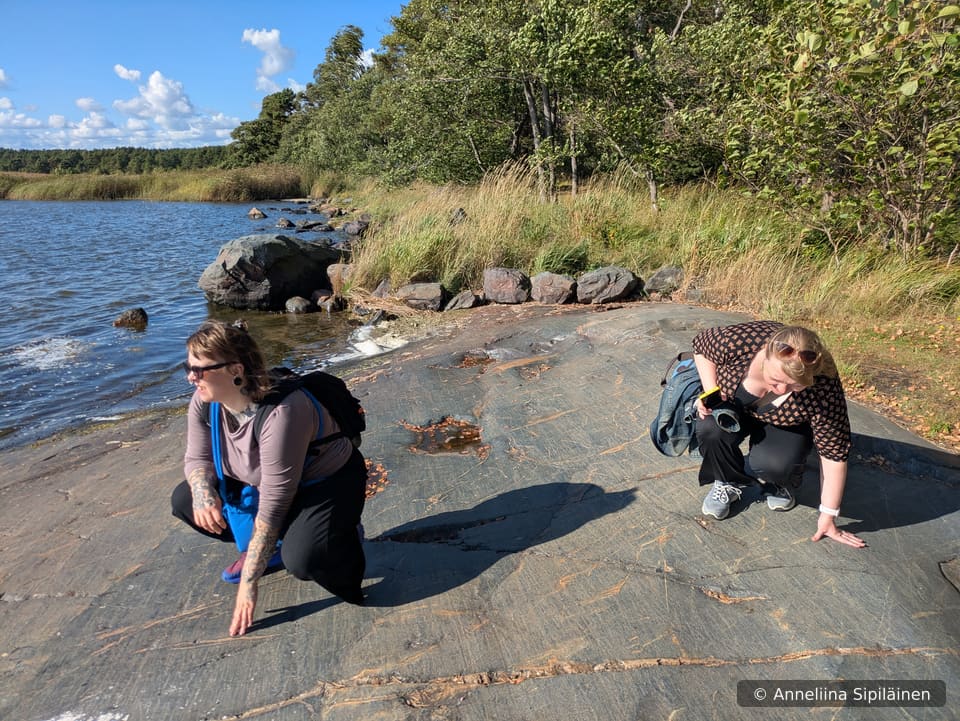 Two ladies testing the smooth surface of a coastal rock smoothened by the Ice age